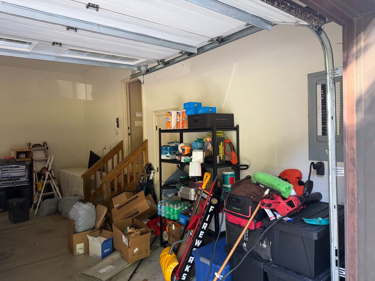 Boxes, bags, and household items stored along a garage wall