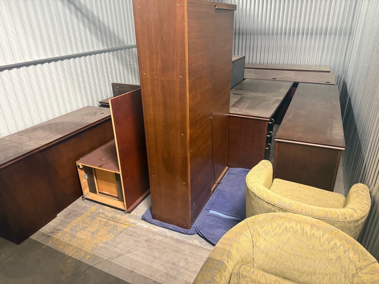 Wood furniture and upholstered chairs filling a storage unit