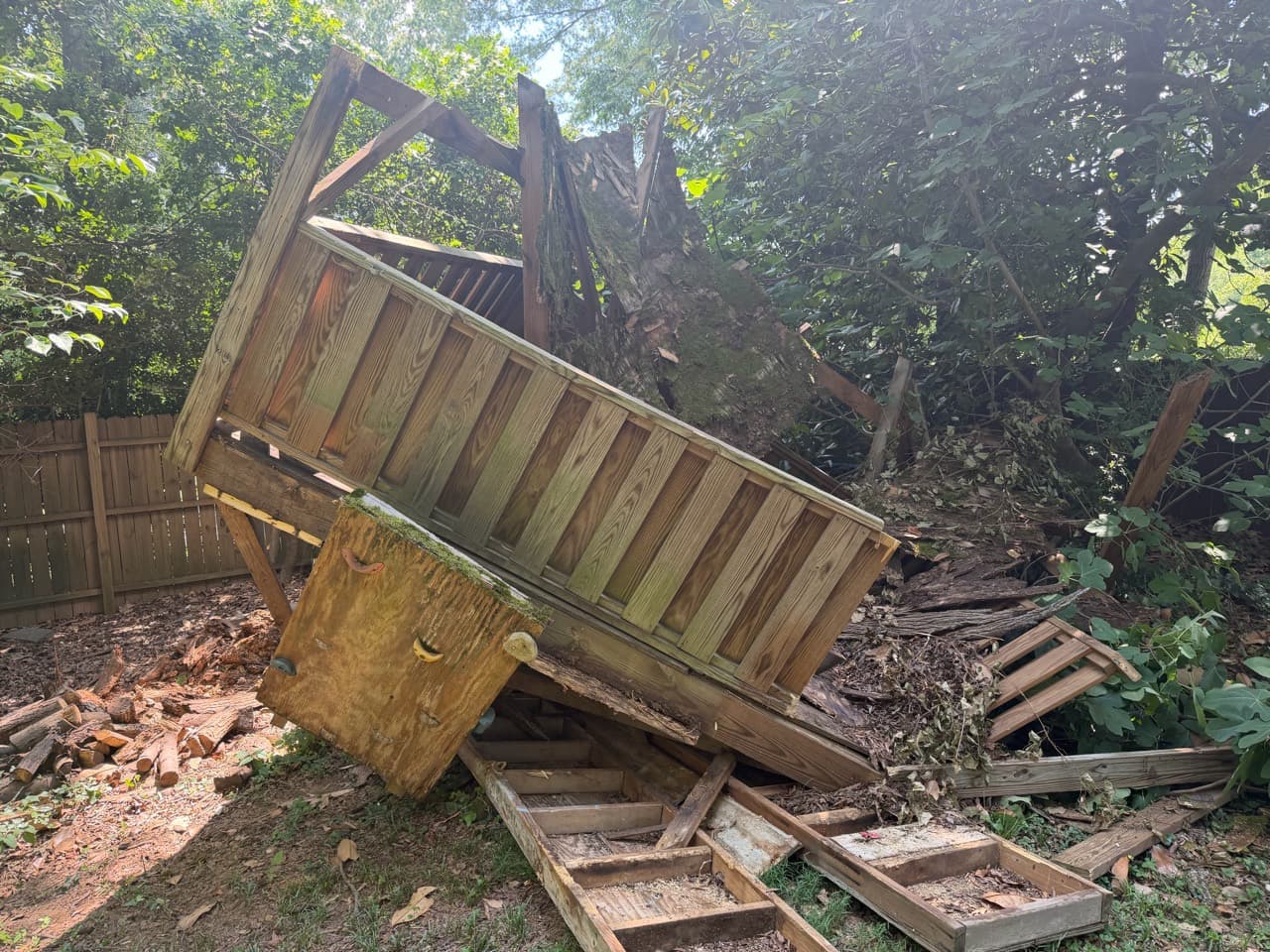 Old wood play structure during removal, with detached sections on the ground